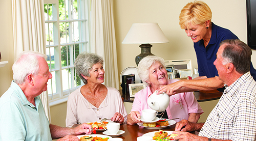 Group Of Senior Couples Enjoying Meal Together In Care Home Group Of Smiling Senior Couples Enjoying Meal Together In Care Home With Home Help.