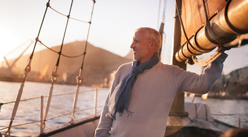 senior man sailing Retired mature man enjoying sailing on his yacht seen staring out at the ocean and enjoying the view